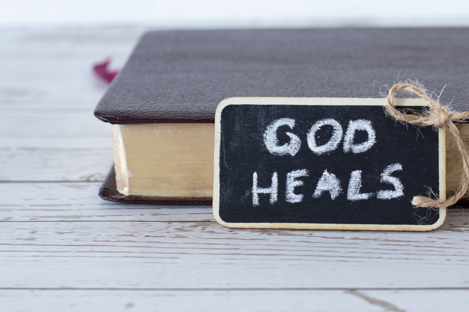 God heals, a handwritten text written with chalk on a small blac
