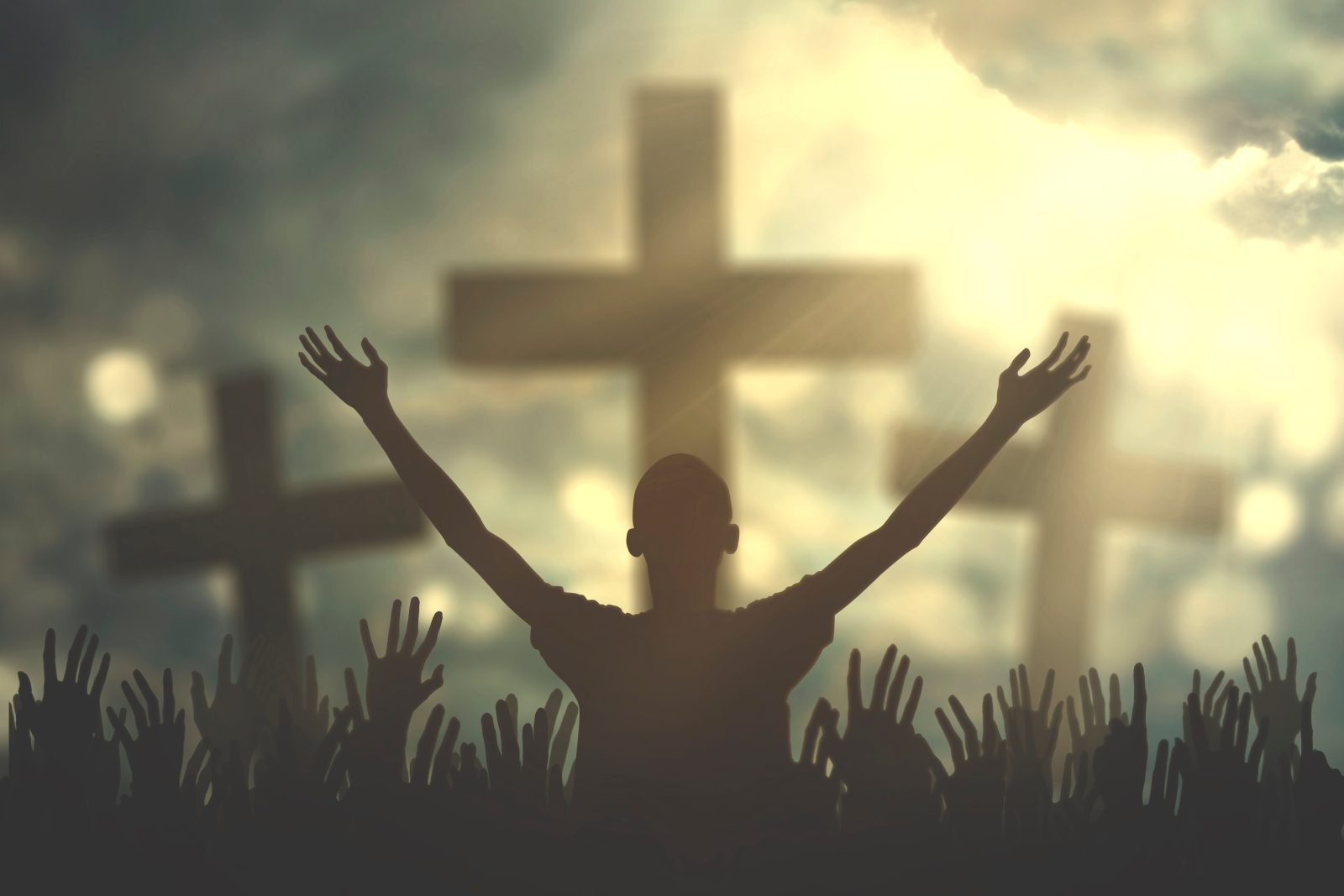 Silhouette of christian prayers raising hand while praying to the GOD with three cross symbols